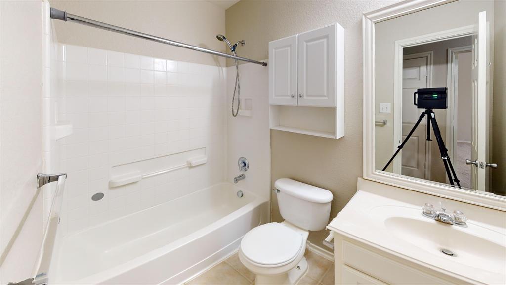 Bathroom featuring a tub and shower combination, wall-mounted storage cabinetry, a vanity with an integrated basin, and a framed mirror