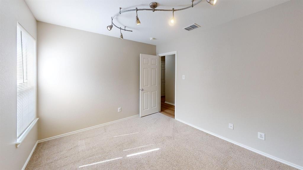 Neutral-toned interior featuring wall-to-wall carpeting, a multi-light track lighting fixture, and a single-panel interior door