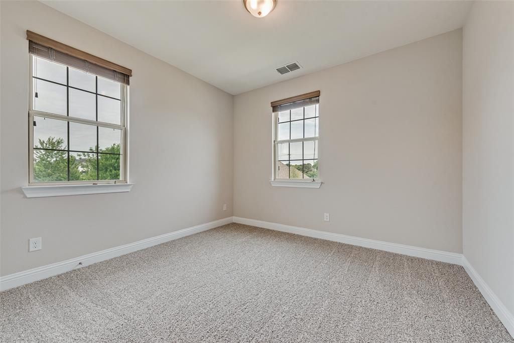 Neutral-toned interior room featuring wall-to-wall carpeting, dual windows with multi-pane grids, and a flush-mount ceiling light fixture