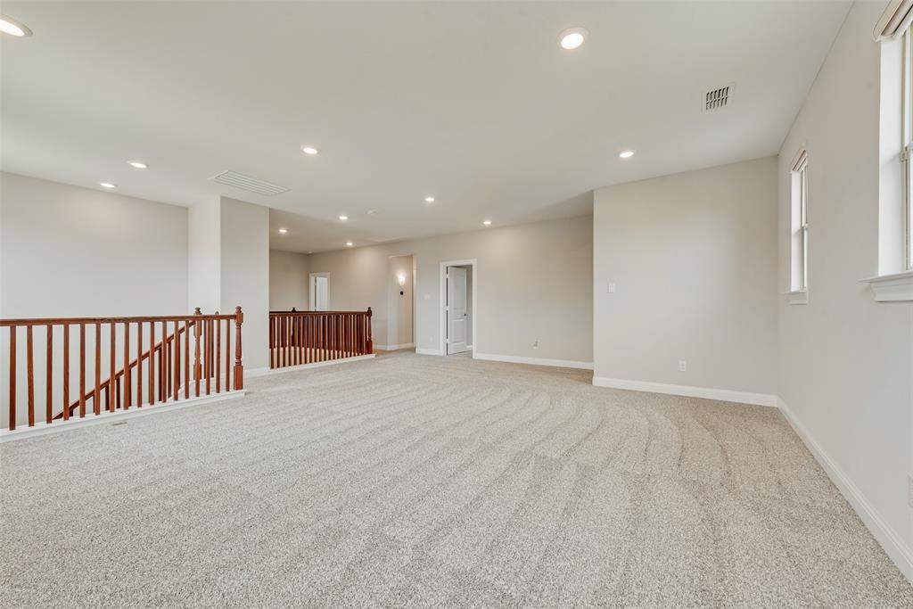 Open floor plan featuring recessed lighting, neutral carpeting, and a wood-slat railing