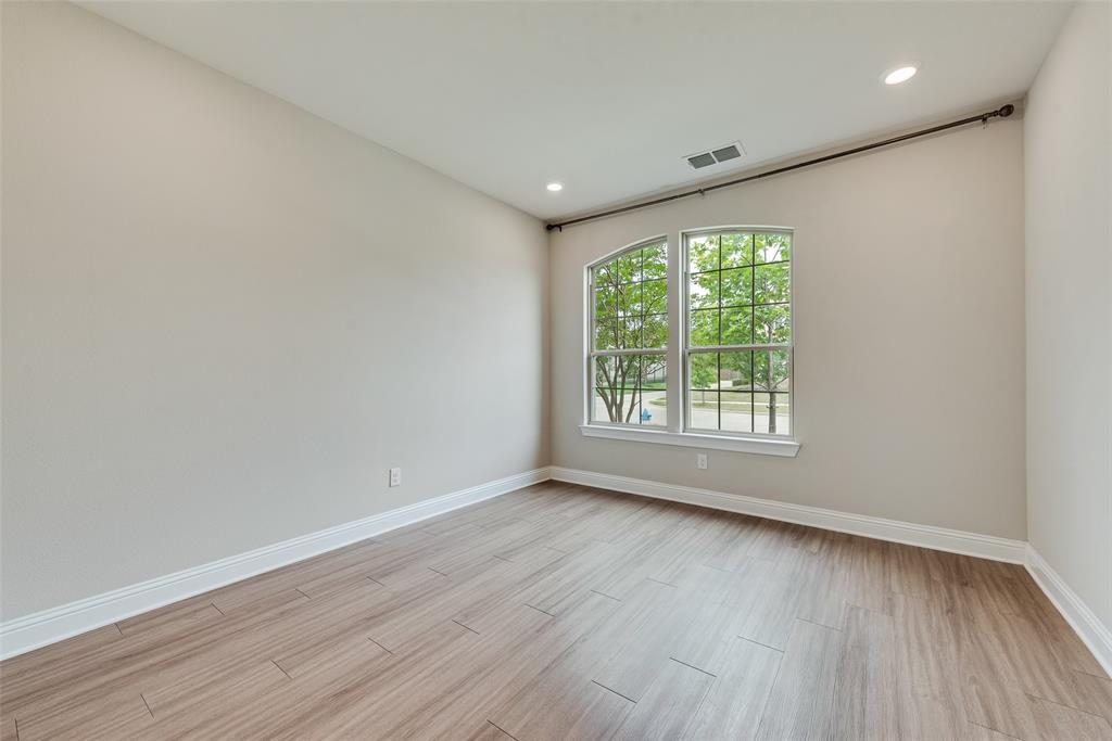 Room featuring wood-finish flooring, recessed lighting, and a multi-pane window with an arched transom