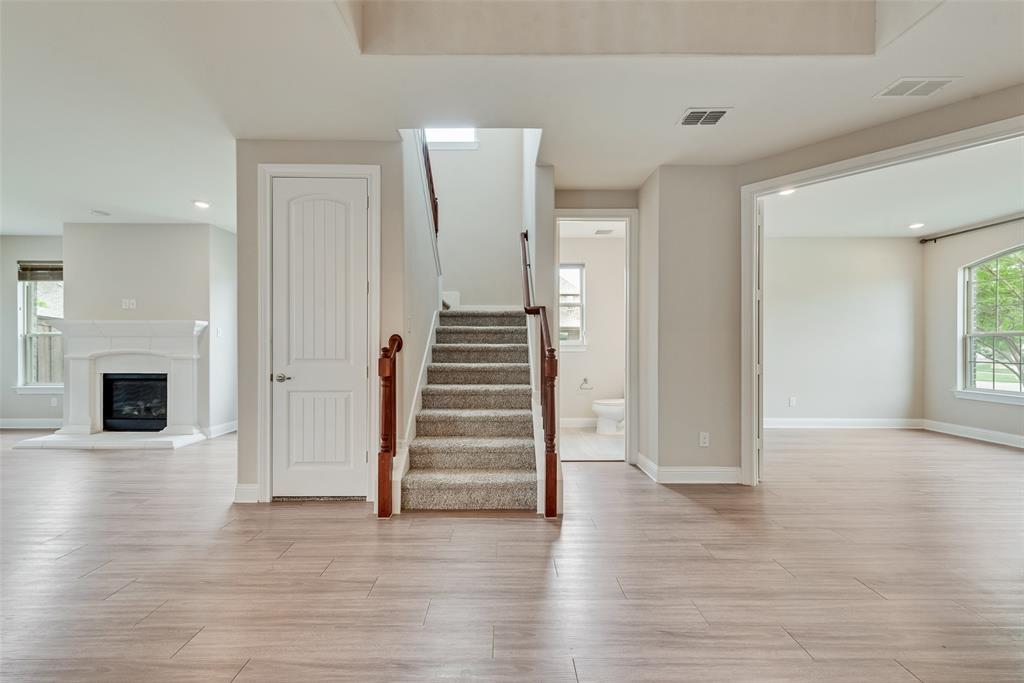 Interior space featuring wood-finish flooring, a white-mantel fireplace, a central staircase with a wood handrail, and arched doorways