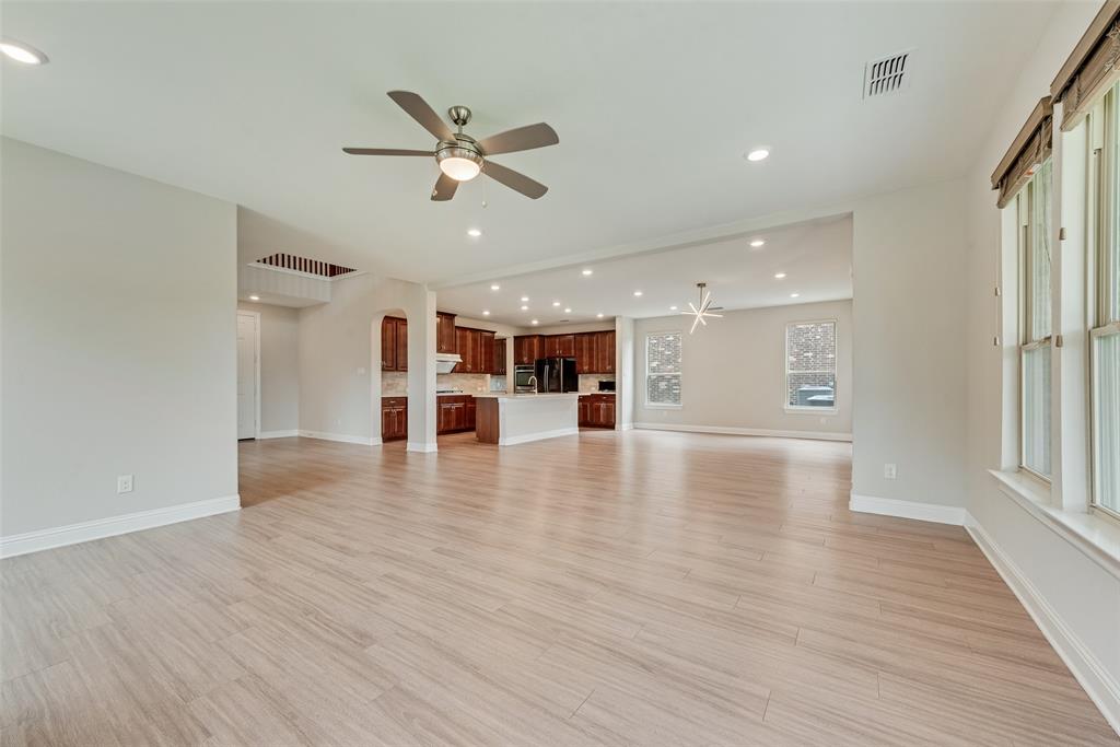 Open-concept interior featuring wood-finish flooring, recessed lighting, a ceiling fan, and a kitchen with dark-finish cabinetry and a central island