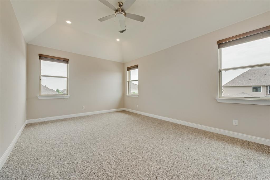 Vaulted ceiling featuring a central brushed-nickel ceiling fan, recessed lighting, neutral carpeting, and multiple windows with installed roller shades