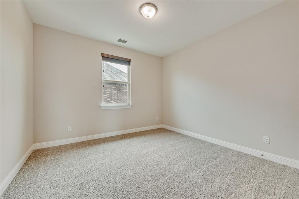 Neutral-toned interior space featuring wall-to-wall carpeting, a single-pane window with a roller shade, and a flush-mount ceiling light fixture
