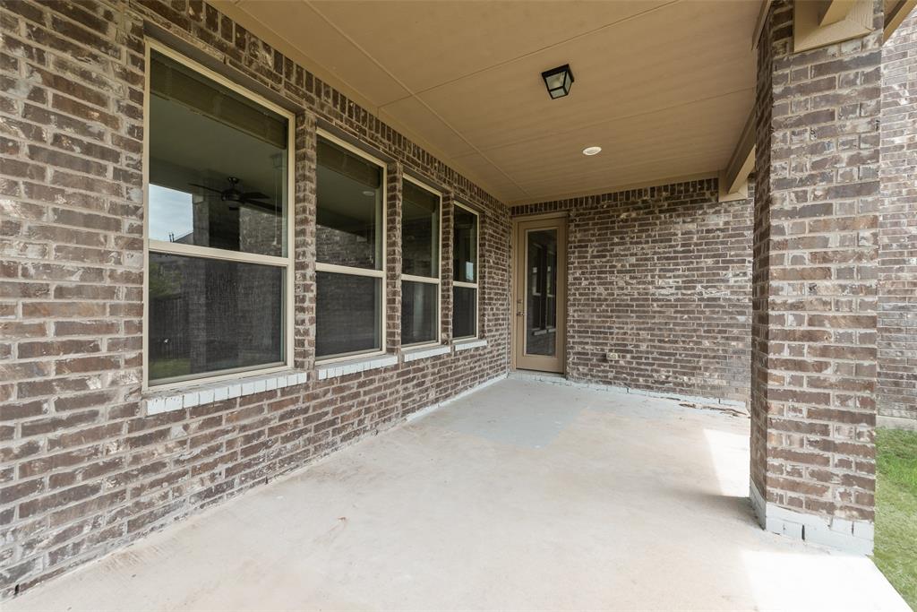 Covered outdoor patio featuring brick masonry walls, concrete flooring, recessed lighting, and multiple tall windows