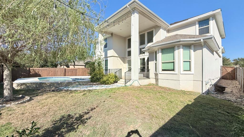 Two-story exterior featuring a light-toned facade, an elevated covered rear porch with a prominent column, multi-pane windows, and a backyard swimming pool enclosed by wooden fencing