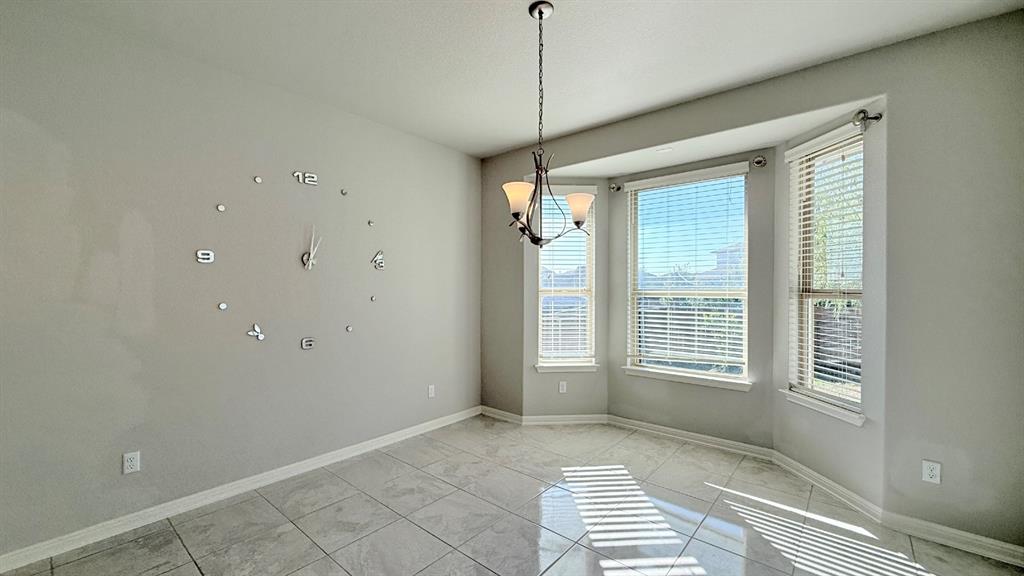 Light-filled room featuring large-format ceramic tile flooring, a multi-pane bay window, and a decorative multi-arm chandelier