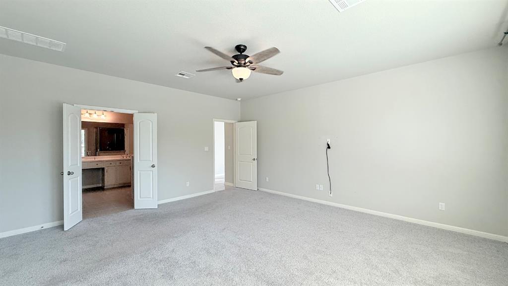 Neutral wall tones, carpeted flooring, multi-speed ceiling fan with integrated lighting, and interior doors with panel detailing