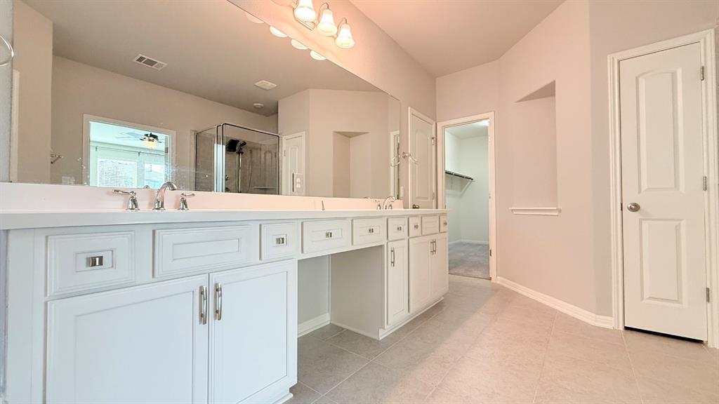 Double vanity featuring white cabinetry, solid-surface countertops, dual undermount sinks, and a full-width mirror
