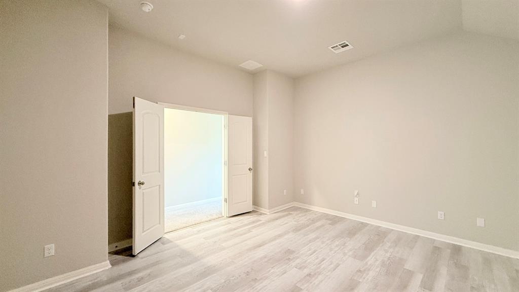 Vaulted ceilings, wood-finish flooring, and white double doors