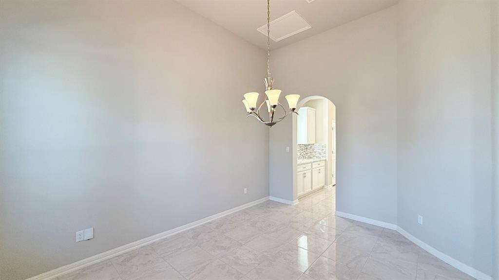High ceilings, polished stone-finish tile flooring, arched entryway, and multi-arm chandelier