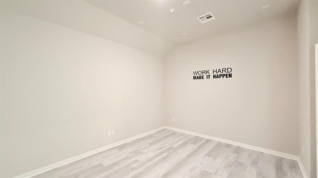 Room featuring high vaulted ceilings, neutral wall tones, and wood-finish flooring