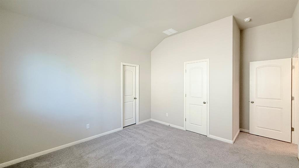 Room featuring vaulted ceilings, neutral wall tones, gray carpeting, and three-panel arched interior doors