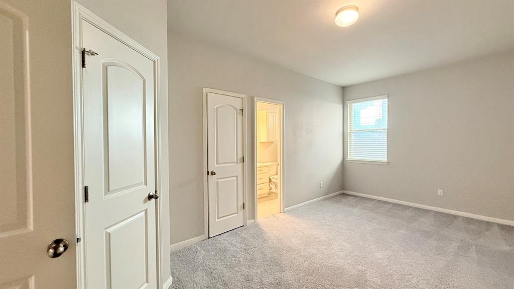 Neutral interior featuring wall-to-wall carpeting, two-panel interior doors, and a window with horizontal blinds