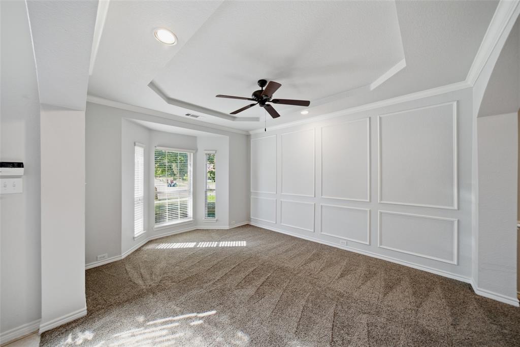 Tray ceiling with integrated recessed lighting, wall molding detail, bay window, and ceiling fan