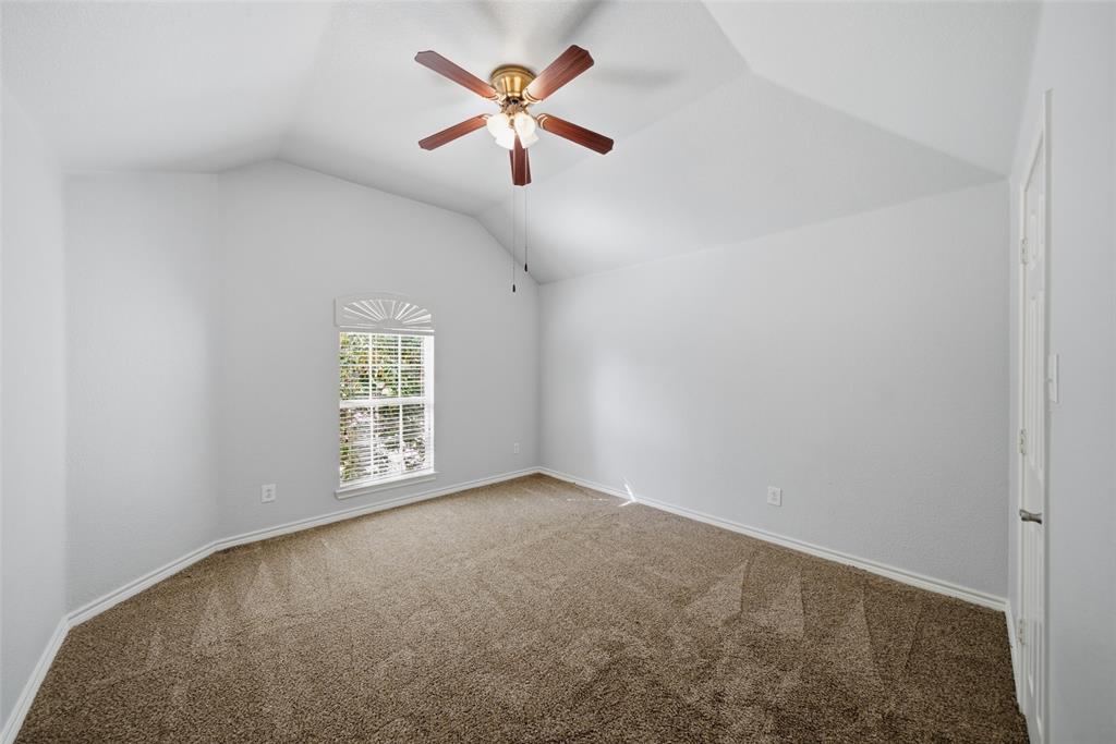 Vaulted ceiling with a central multi-blade ceiling fan, arched window, and neutral wall-to-wall carpeting