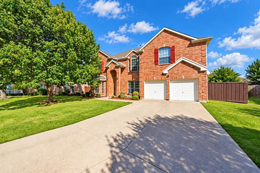 Two-story brick exterior featuring a multi-gabled roofline, decorative window shutters, an arched entryway, and an attached two-car garage