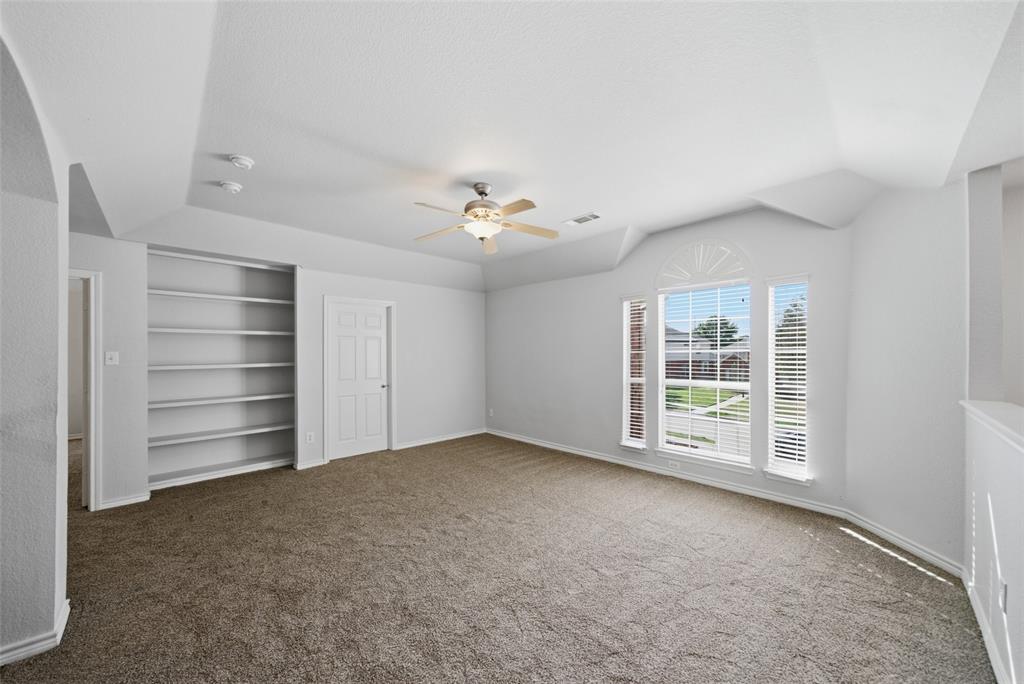 Tray ceiling, built-in recessed shelving, ceiling fan with integrated lighting, and multi-pane windows with arched detailing