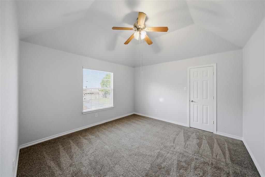 Vaulted ceiling featuring a ceiling fan with integrated lighting, neutral carpeting, and a multi-panel interior door