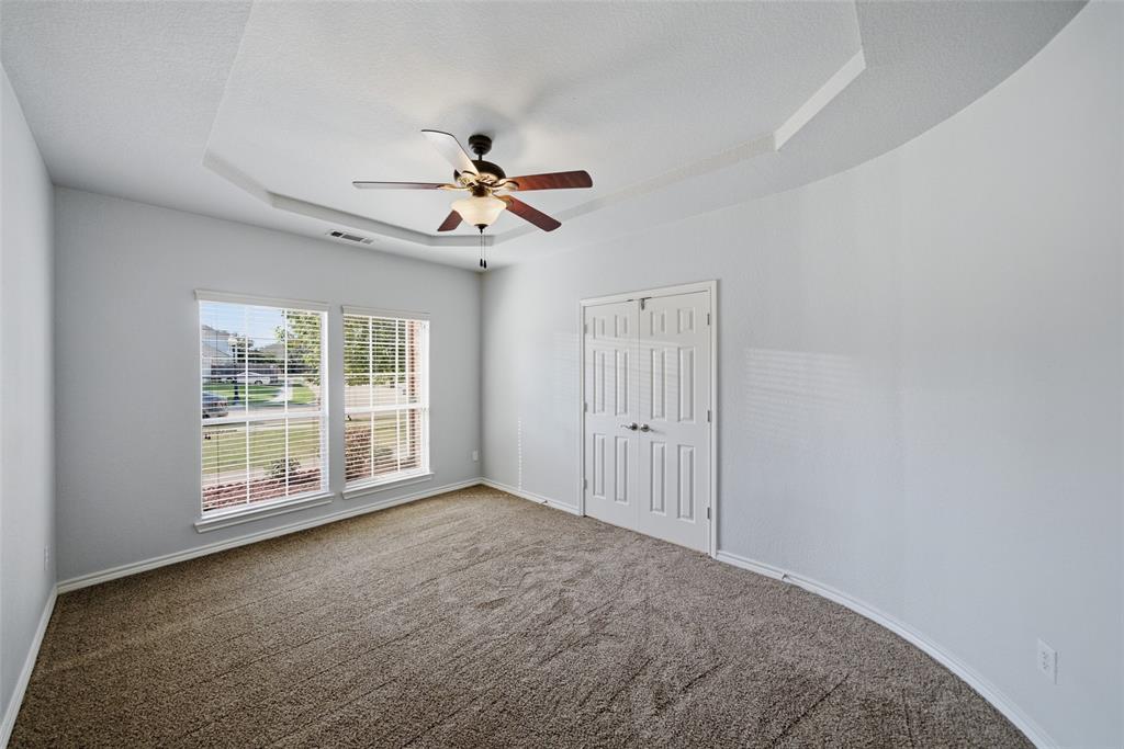 Tray ceiling, dual-pane windows, ceiling fan with light fixture, and double-door closet