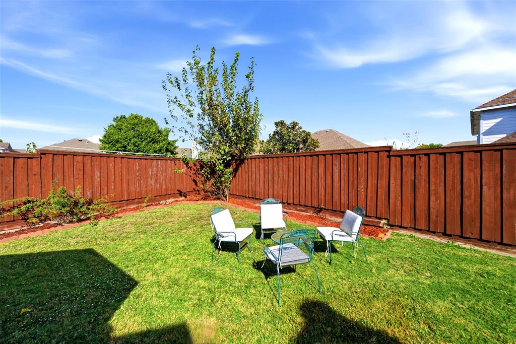 Backyard featuring a manicured lawn, perimeter wood fencing, and established trees