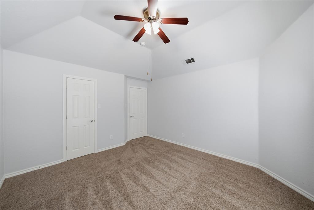 Vaulted ceiling featuring a central multi-blade ceiling fan with integrated light fixture, neutral wall finishes, and carpeted flooring