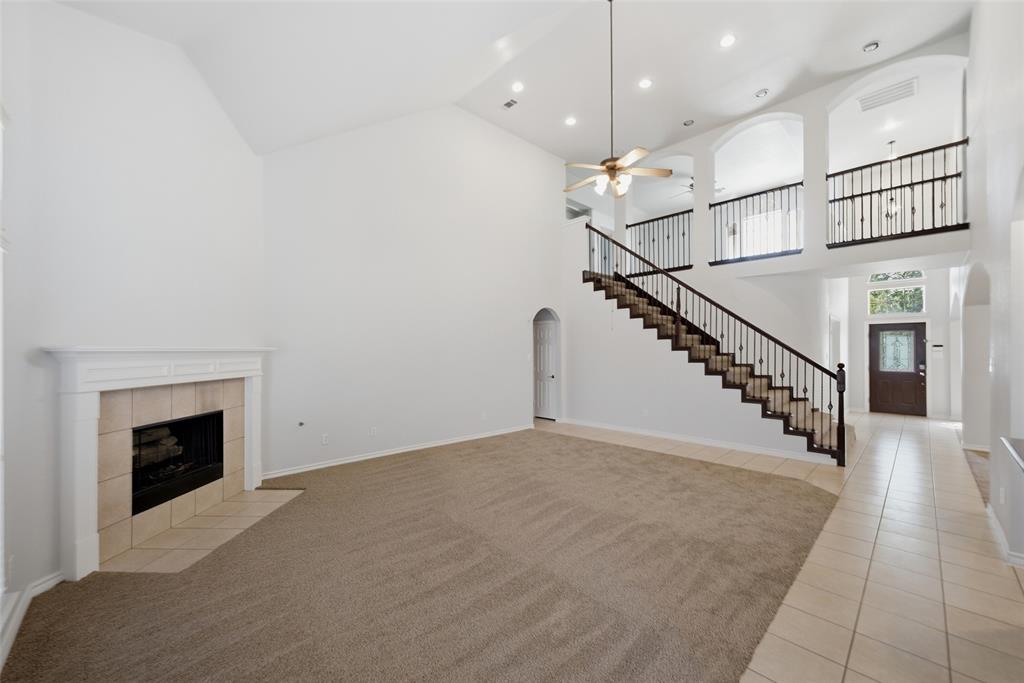 Vaulted ceilings, fireplace with custom-milled mantel, open-staircase with wrought iron balusters, arched architectural detailing, and recessed lighting