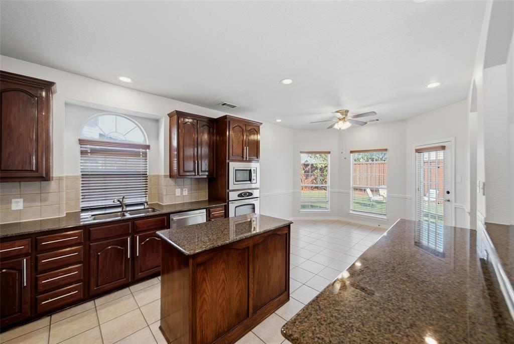 Kitchen featuring dark wood cabinetry, stone countertops, an island, recessed lighting, and tile flooring