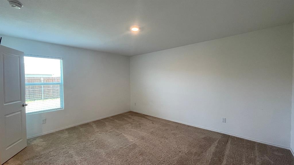 Neutral wall-to-wall carpeting, crisp white wall finishes, single-pane window, and a multi-panel interior door