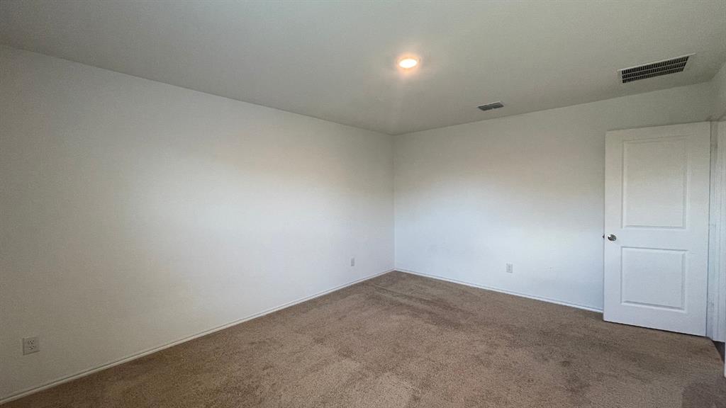Neutral interior space featuring carpeted flooring, white walls, and a two-panel interior door