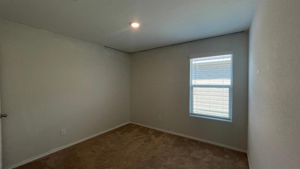 Neutral-toned interior space featuring wall-to-wall carpeting, a single-pane window with horizontal blinds, and a recessed ceiling light fixture