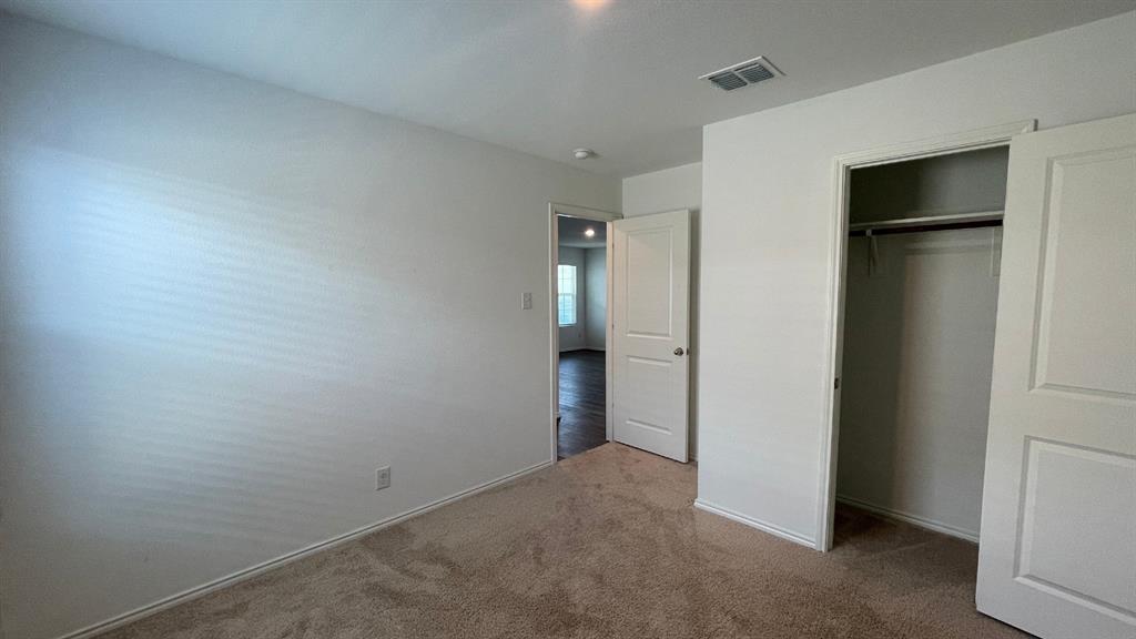 Neutral-toned carpeted flooring, two-panel interior doors, and a built-in closet with overhead shelving