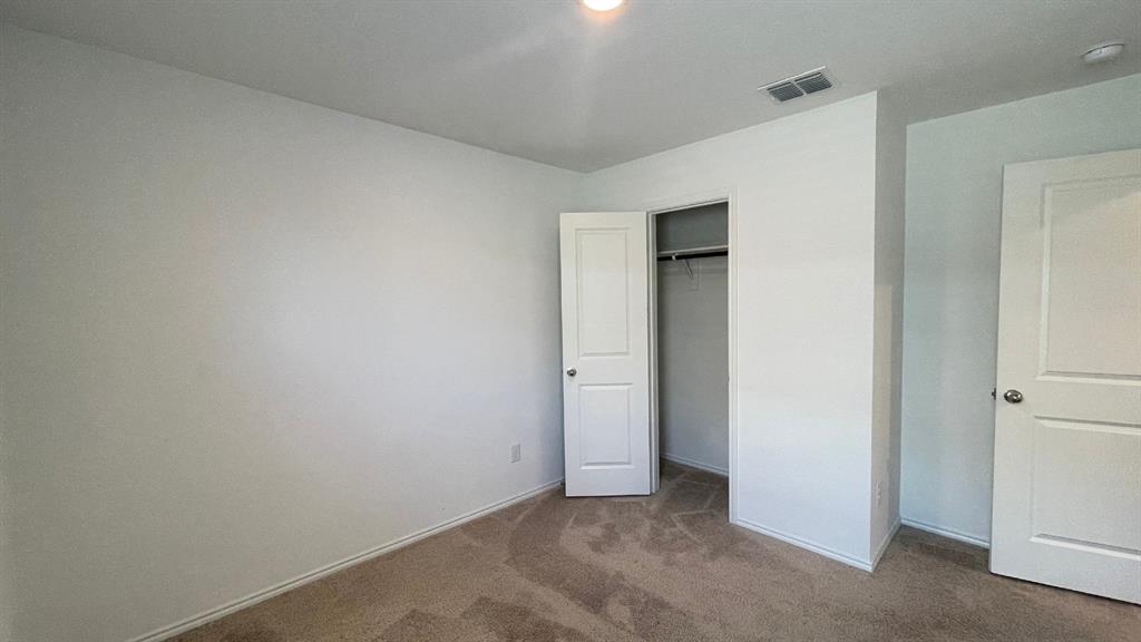 Neutral-toned wall-to-wall carpeting, two-panel interior doors, and a built-in closet with an integrated garment rod