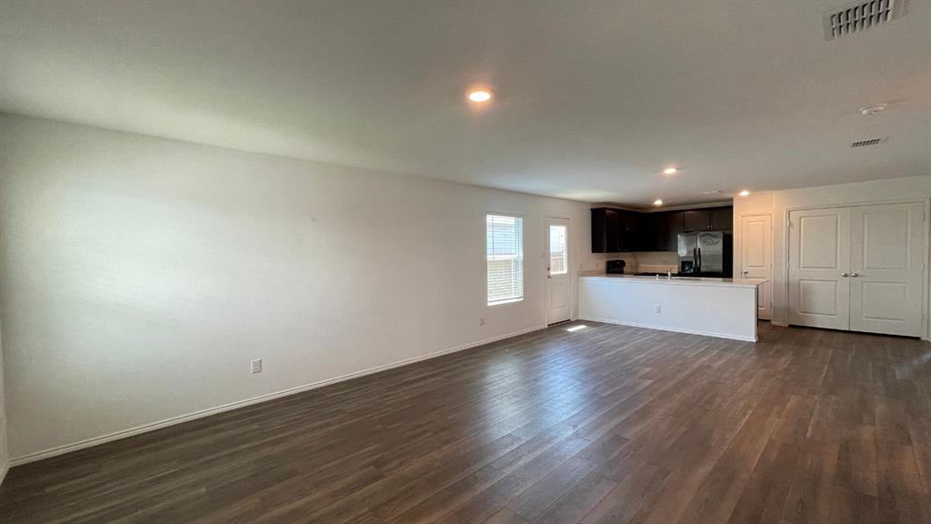 Open-concept interior featuring wood-finish flooring, recessed lighting, and a kitchen with dark cabinetry and a breakfast bar