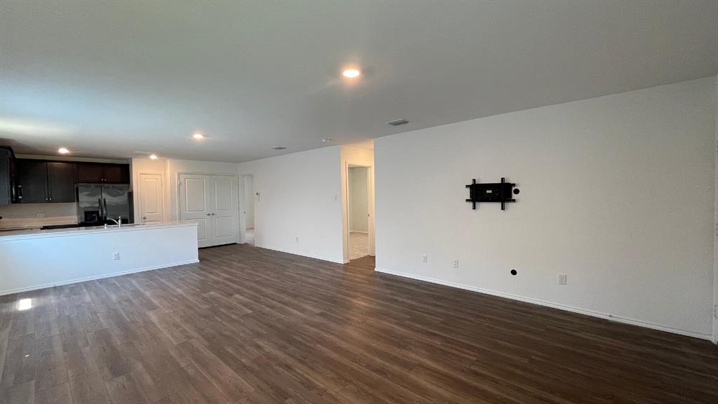 Open-concept interior featuring wood-finish flooring, recessed lighting, and a kitchen peninsula with dark cabinetry