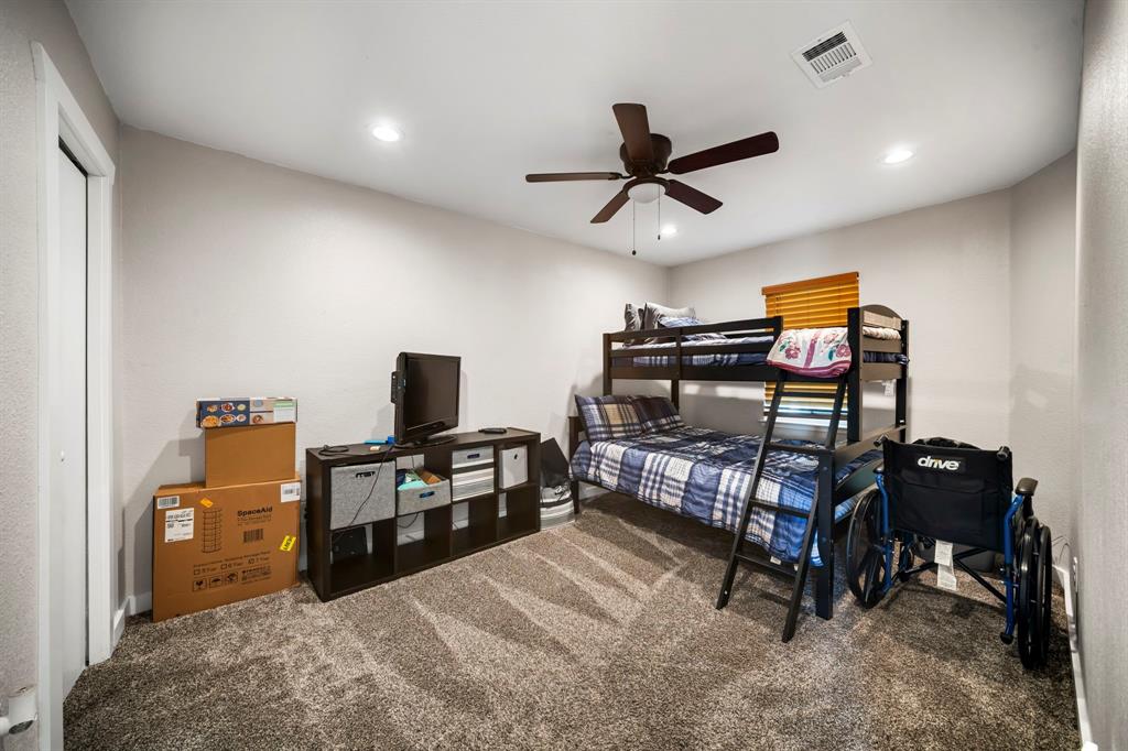 Neutral-toned room featuring textured wall-to-wall carpeting, recessed ceiling lighting, and a dark-finish ceiling fan