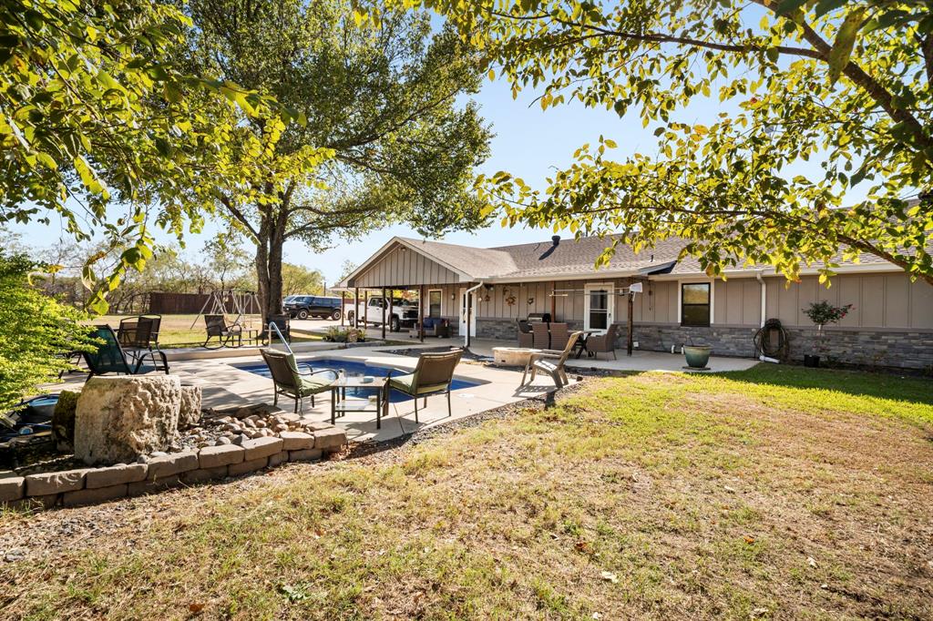 Exterior featuring an in-ground swimming pool, stone-veneer siding, concrete patio, and a covered porch area