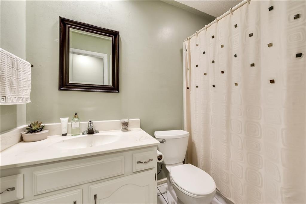 Bathroom featuring a white vanity with integrated basin, solid-surface countertop, dark-framed wall mirror, and porcelain toilet