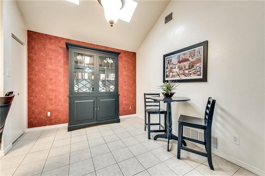 Vaulted ceiling with a recessed light fixture, built-in dark-toned hutch, and tile flooring