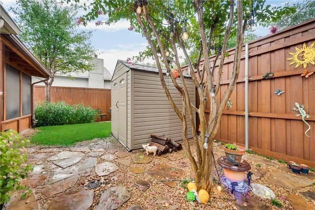 Rear yard featuring a flagstone patio, lawn area, storage shed, and full-height wood privacy fencing