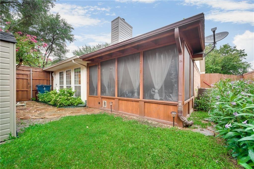 Screened-in porch with wood-paneled base, exterior lawn, stone-paved walkway, and privacy wood fencing