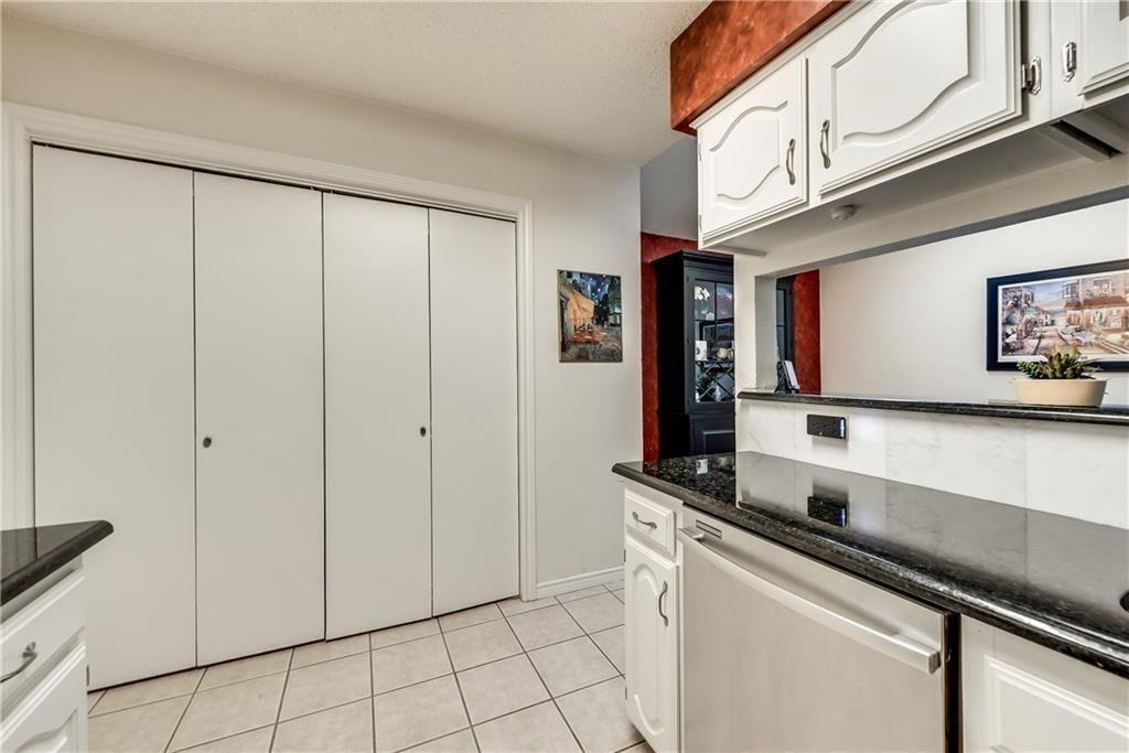 Kitchen featuring white cabinetry, dark stone-finish countertops, tile flooring, and integrated white bifold closet doors