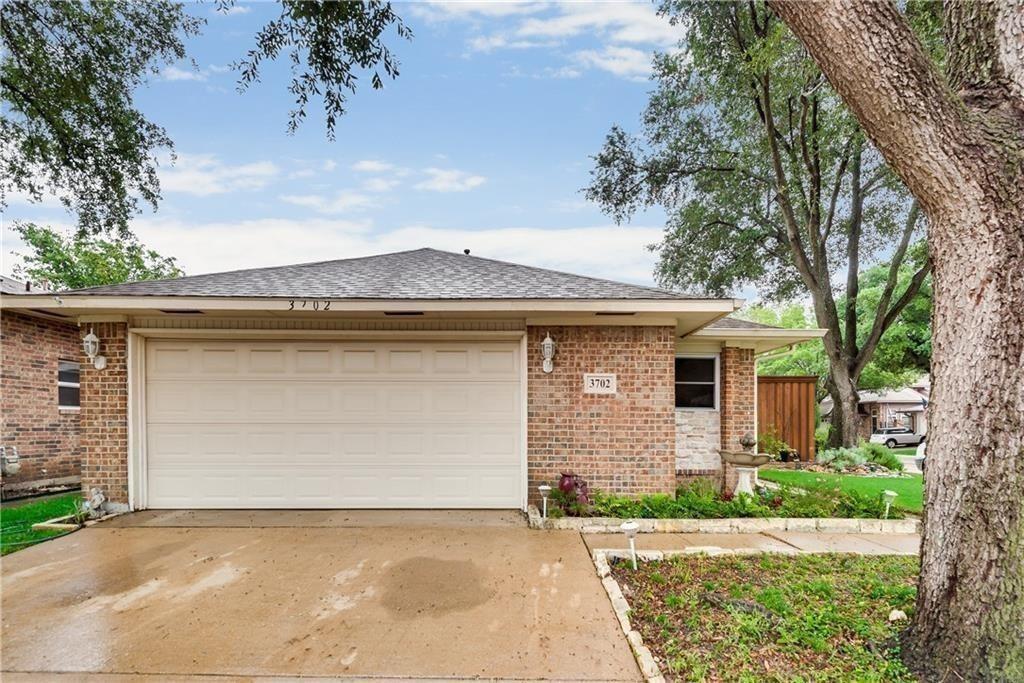 Brick exterior featuring an attached two-car garage, concrete driveway, stone accents, and shingled roof