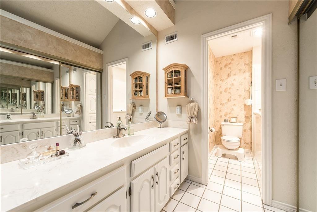 Full-width vanity featuring a solid surface countertop, integrated sink, white cabinetry, wall-to-wall mirror, and wall-mounted wooden storage cabinet