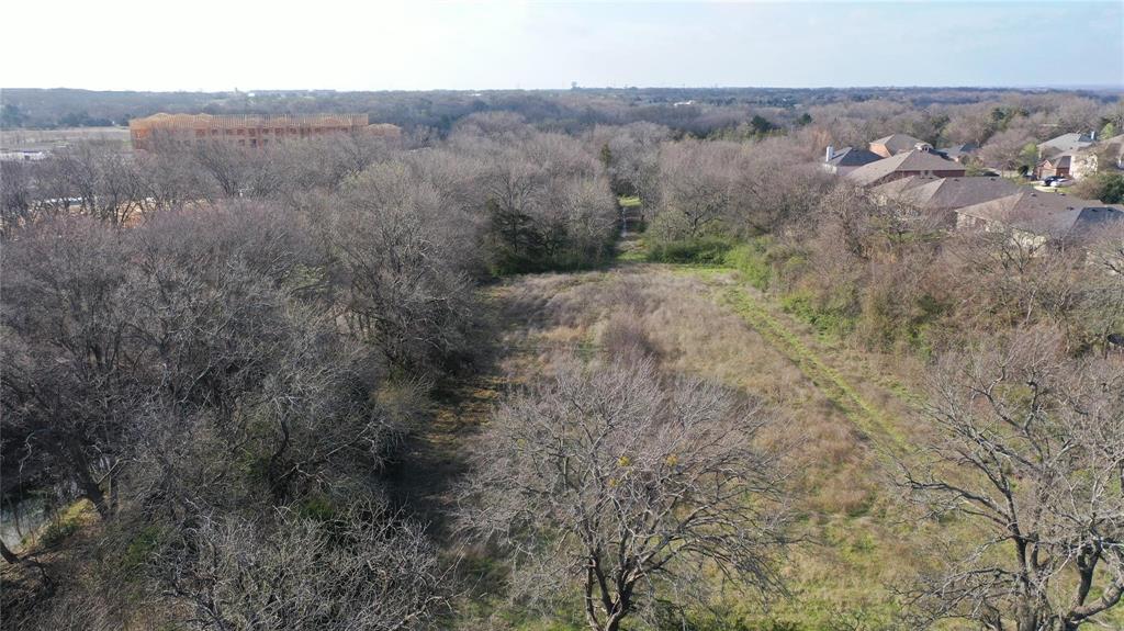 Expansive parcel with mature trees and a cleared central area, offering views of surrounding development and residential properties