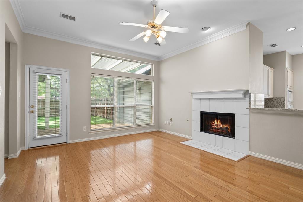 Unfurnished living room featuring a tile fireplace, crown molding, ceiling fan, and light wood-style flooring