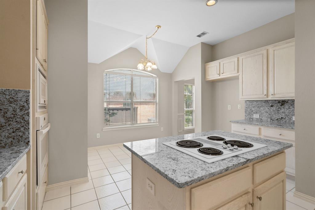 Kitchen featuring white appliances, a chandelier, light stone countertops, light tile patterned floors, and vaulted ceiling