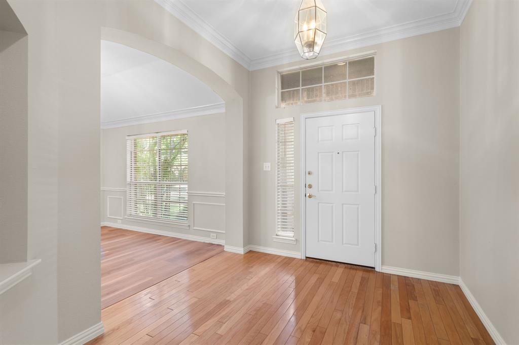 Foyer entrance with light wood-style floors, arched walkways, and ornamental molding