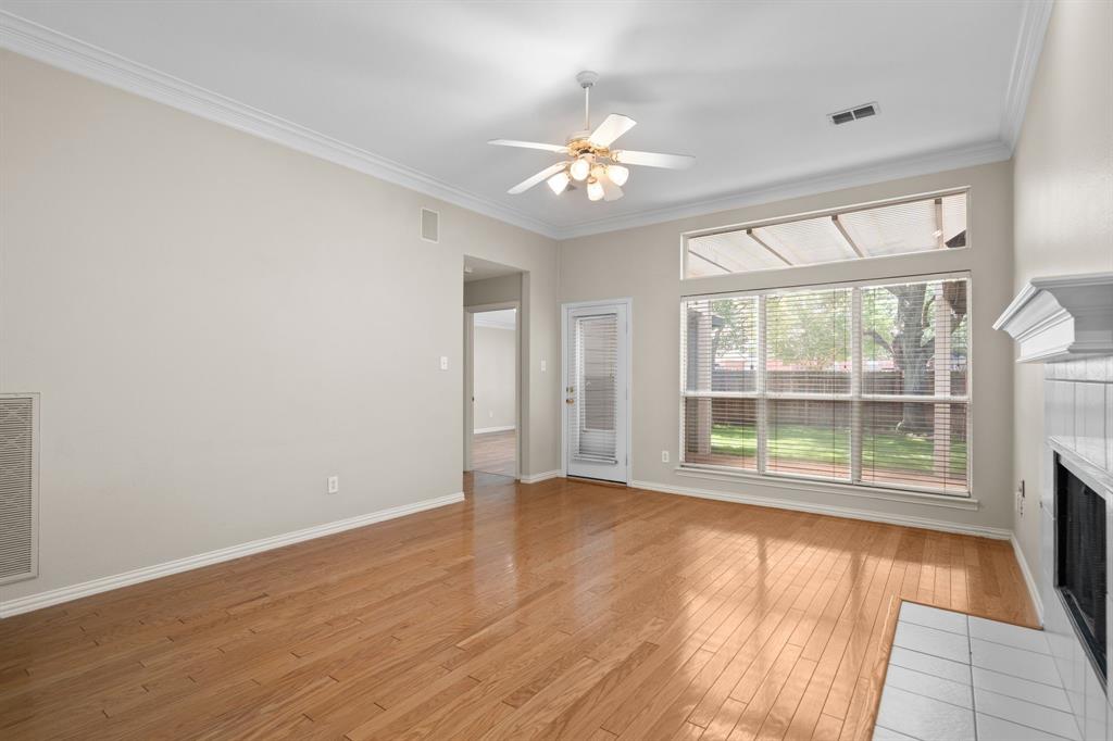 Unfurnished living room featuring a tile fireplace, crown molding, light wood-type flooring, and ceiling fan